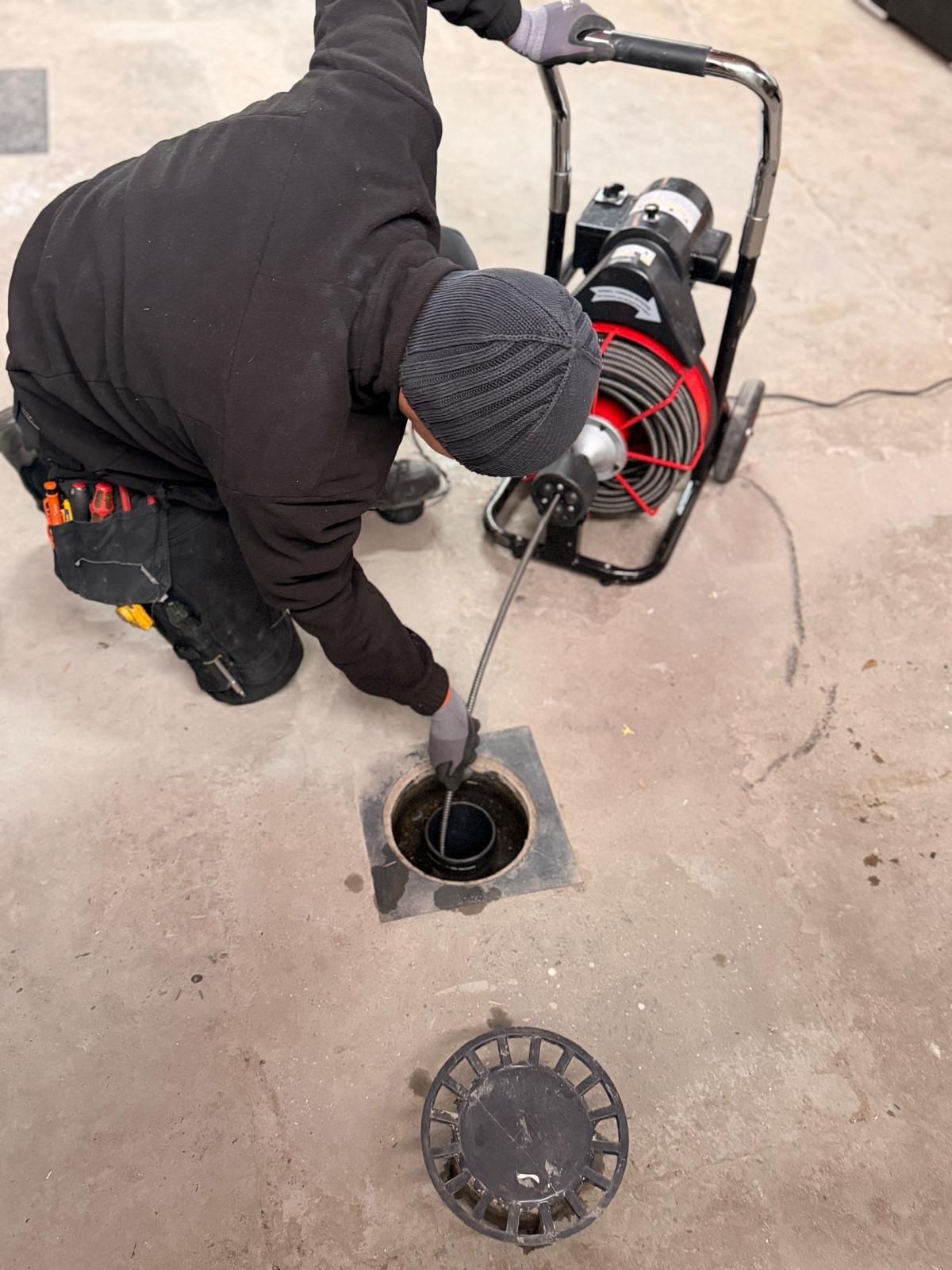 Plumby-loodgieter ontstopt een riool met de ontstoppingsmachine